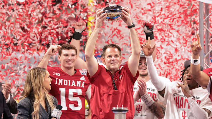Indiana coach Curt Cignetti holds up the Peach Bowl trophy as quarterback Fernando Mendoza and the Hoosiers look on.