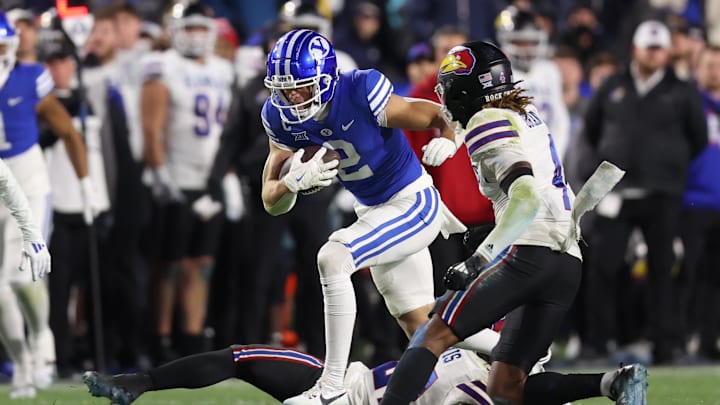 Nov 16, 2024; Provo, Utah, USA; Brigham Young Cougars wide receiver Chase Roberts (2) breaks a tackle by Kansas Jayhawks safety Taylor Davis (bottom) and safety Marvin Grant (4) defends during the fourth quarter at LaVell Edwards Stadium. Mandatory Credit: Rob Gray-Imagn Images