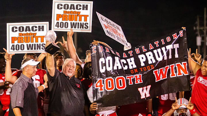 Williston Red Devils head coach Robby Pruitt hoists a glass football into the air after winning his 400th game. The Williston Red Devils hosted Trinity Catholic Celtics at Booster Stadium in Williston, FL on Monday, September 30, 2024. [Doug Engle/Ocala Star Banner]