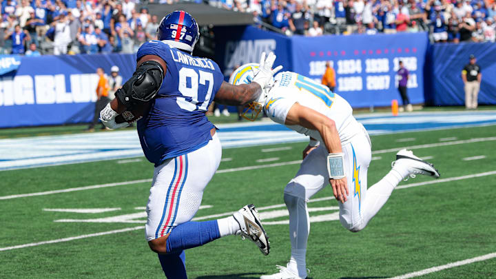 Sep 28, 2025; East Rutherford, New Jersey, USA; New York Giants defensive tackle Dexter Lawrence (97) is tackled by Los Angeles Chargers quarterback Justin Herbert (10) after intercepting a pass during the first half at MetLife Stadium. Mandatory Credit: Vincent Carchietta-Imagn Images