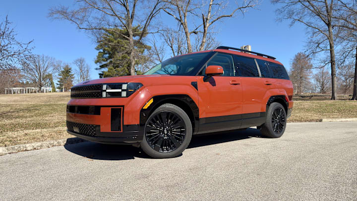A three quarter shot of a 2025 Hyundai Santa Fe Hybrid Calligraphy AWD in Terracotta Orange paint.