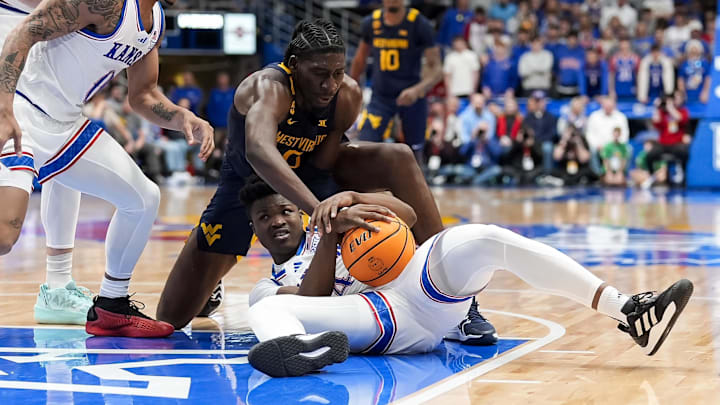 Dec 31, 2024; Lawrence, Kansas, USA; Kansas Jayhawks guard Rakease Passmore (4) and West Virginia Mountaineers center Eduardo Andre (0) fight for a loose ball during the first half at Allen Fieldhouse. Mandatory Credit: Jay Biggerstaff-Imagn Images