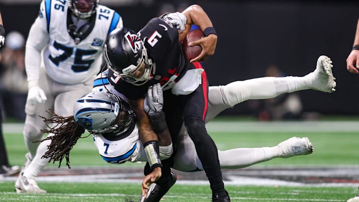 Jan 5, 2025; Atlanta, Georgia, USA; Carolina Panthers linebacker Jadeveon Clowney (7) tackles Atlanta Falcons quarterback Michael Penix Jr. (9) in the third quarter at Mercedes-Benz Stadium. Mandatory Credit: Brett Davis-Imagn Images