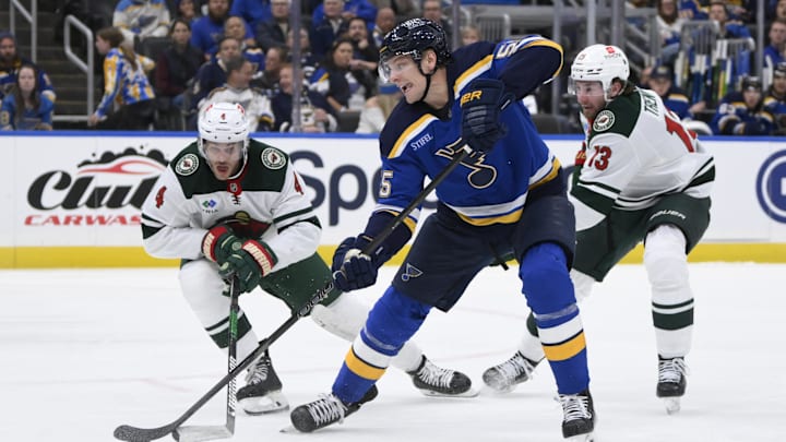 Oct 15, 2024; St. Louis, Missouri, USA; St. Louis Blues defenseman Colton Parayko (55) battles Minnesota Wild defenseman Jon Merrill (4) and center Yakov Trenin (13) during the second period at Enterprise Center. Mandatory Credit: Jeff Le-Imagn Images