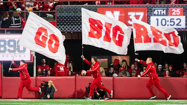 Nov 23, 2024; Lincoln, Nebraska, USA; Nebraska Cornhuskers cheerleaders carry flags across the field after a score against the Wisconsin Badgers during the fourth quarter at Memorial Stadium. 