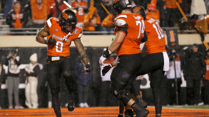 Nov 25, 2023; Stillwater, Oklahoma, USA;  Oklahoma State's Ollie Gordon II (0) celebrates with Oklahoma State's Preston Wilson (74) and Rashod Owens (10) after scoring a touchdown during the second overtime against the Brigham Young Cougars at Boone Pickens Stadium. Mandatory Credit: Sarah Phipps-USA TODAY Sports