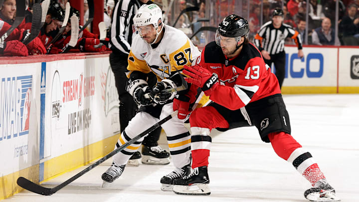 Sidney Crosby (87) and Nico Hischier (13) engage in a puck battle along the wall