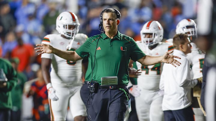 Oct 14, 2023; Chapel Hill, North Carolina, USA; Miami Hurricanes head coach Mario Cristobal stands on the field during a timeout as the Hurricanes play against the North Carolina Tar Heels in the second half at Kenan Memorial Stadium. Mandatory Credit: Nell Redmond-Imagn Images Oct 14, 2023; Chapel Hill, North Carolina, USA; Miami Hurricanes head coach Mario Cristobal stands on the field during a timeout as the Hurricanes play against the North Carolina Tar Heels in the second half at Kenan Memorial Stadium. Mandatory Credit: Nell Redmond-Imagn Images
