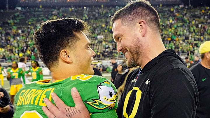 Oregon quarterback Dillon Gabriel, left, and coach Dan Lanning embrace after defeating Maryland at Autzen Stadium.