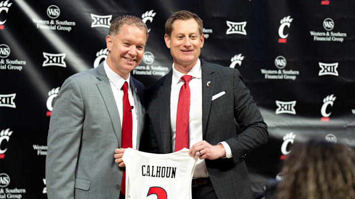 University of Cincinnati athletic director John Cunningham stands with Cincinnati head coach Jerrod Calhoun with a jersey as he is announced as the head men's basketball coach at Fifth Third Arena in Cincinnati on Wednesday, March 25, 2026. University of Cincinnati athletic director John Cunningham stands with Cincinnati head coach Jerrod Calhoun with a jersey as he is announced as the head men's basketball coach at Fifth Third Arena in Cincinnati on Wednesday, March 25, 2026.
