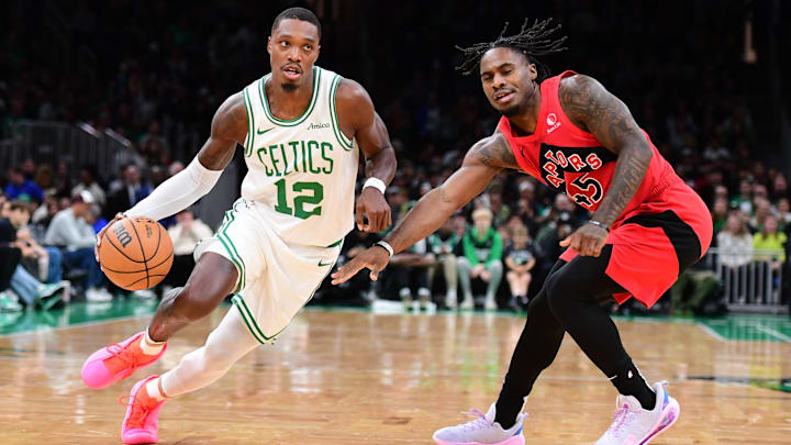 Oct 13, 2024; Boston, Massachusetts, USA;  Boston Celtics guard Lonnie Walker IV (12) controls the ball while Toronto Raptors guard Davion Mitchell (45) defends during the first half at TD Garden. Mandatory Credit: Bob DeChiara-Imagn Images