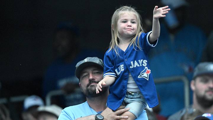 A young Toronto Blue Jays fan enjoys the seventh inning stretch on her fathers shoulders. A young Toronto Blue Jays fan enjoys the seventh inning stretch on her fathers shoulders.