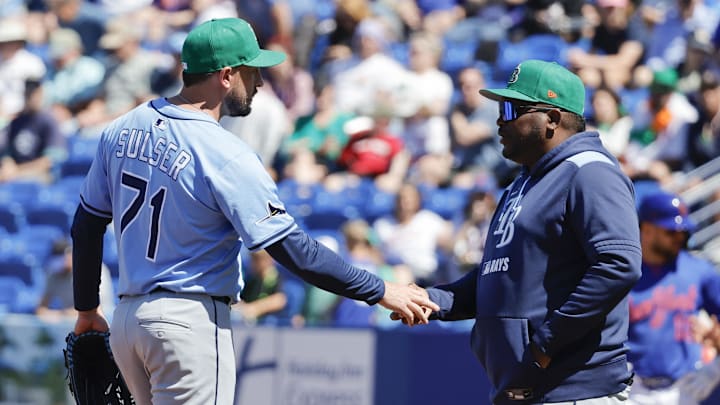 Tampa Bay pitcher Cole Sulser (left) hands the ball to bench coach Rodney Linares during a spring training game in March 2025.