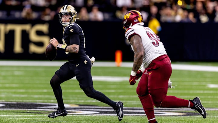 Dec 15, 2024; New Orleans, Louisiana, USA;  New Orleans Saints quarterback Spencer Rattler (18) scrambles against Washington Commanders defensive tackle Daron Payne (94) during the second half at Caesars Superdome. Mandatory Credit: Stephen Lew-Imagn Images