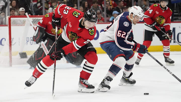 Dec 1, 2024; Chicago, Illinois, USA; Columbus Blue Jackets right wing Kevin Labanc (62) and Chicago Blackhawks center Philipp Kurashev (23) go for the puck during the second period at United Center. Mandatory Credit: David Banks-Imagn Images