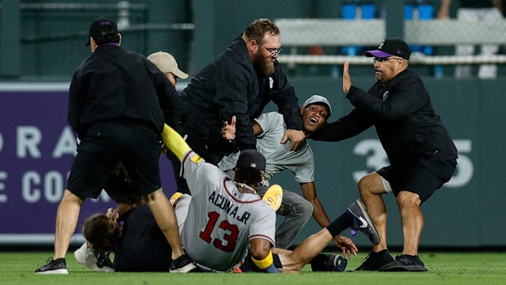 Aug 28, 2023; Denver, Colorado, USA; A fan charges at Atlanta Braves right fielder Ronald Acuna Jr.
