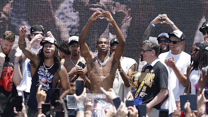 Jun 24, 2025; Oklahoma City, OK, USA; Oklahoma City Thunder guard Shai Gilgeous-Alexander, center, holds up a heart shape with his hands for fans during the Oklahoma City Thunder Champions parade. Center. Mandatory Credit: Alonzo Adams-Imagn Images