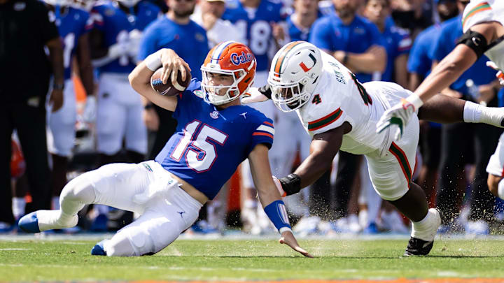 Aug 31, 2024; Gainesville, Florida, USA; Florida Gators quarterback Graham Mertz (15) slides for a first down while Miami Hurricanes defensive lineman Rueben Bain Jr. (4) attempts to tackle during the first half at Ben Hill Griffin Stadium. Mandatory Credit: Matt Pendleton-Imagn Images