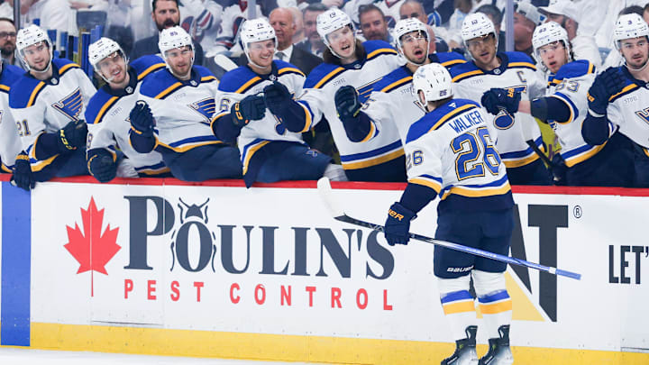 Apr 30, 2025; Winnipeg, Manitoba, CAN; St. Louis Blues forward Nathan Walker (26) is congratulated by his teammates on his goal against Winnipeg Jets goalie Connor Hellebuyck (37) during the first period in game five of the first round of the 2025 Stanley Cup Playoffs at Canada Life Centre. Mandatory Credit: Terrence Lee-Imagn Images
