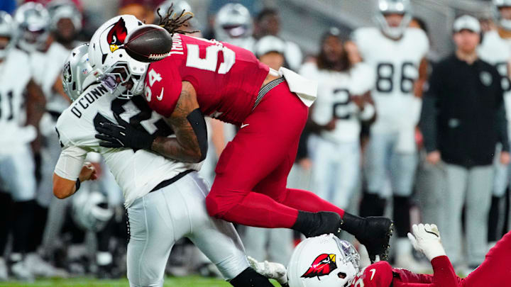 Cardinals edge rushers Jordan Burch (52) and Xavier Thomas (54) force a fumble on Raiders quarterback Aidan O’Connell (12) during a preseason game at State Farm Stadium in Glendale on Aug. 23, 2025.