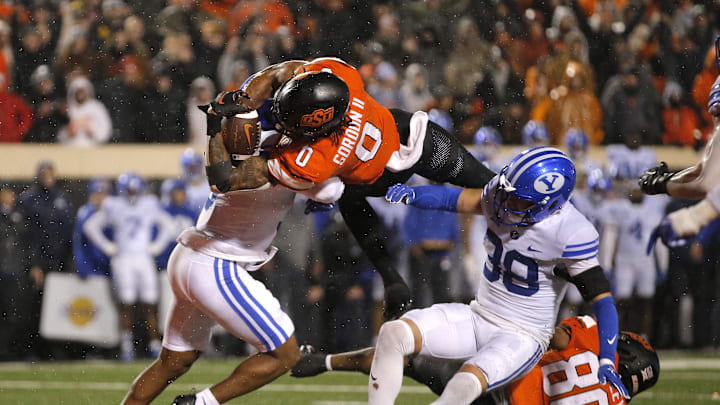 Nov 25, 2023; Stillwater, Oklahoma, USA;  Oklahoma State's Ollie Gordon II (0) scores a touchdown in the second overtime against BYU's Eddie Heckard (5) and Crew Wakley (38) at Boone Pickens Stadium. Mandatory Credit: Sarah Phipps-Imagn Images