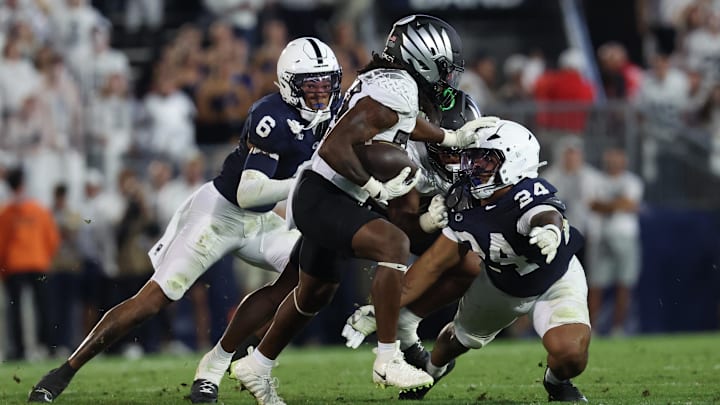 Sep 27, 2025; University Park, Pennsylvania, USA; Oregon Ducks running back Dierre Hill Jr. (23) runs for a gain past Penn State Nittany Lions linebacker Amare Campbell (24) during the second quarter at Beaver Stadium. Mandatory Credit: Matthew O'Haren-Imagn Images