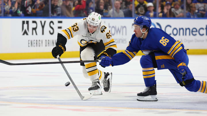 Mar 25, 2026; Buffalo, New York, USA;  Buffalo Sabres center Noah Ostlund (86) and Boston Bruins center Fraser Minten (93) go after a loose puck during the third period at KeyBank Center. Mandatory Credit: Timothy T. Ludwig-Imagn Images