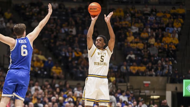 Feb 28, 2026; Morgantown, West Virginia, USA; West Virginia Mountaineers forward DJ Thomas (5) shoots a three pointer over BYU Cougars guard Aleksej Kostić (6) during the second half at Hope Coliseum. Mandatory Credit: Ben Queen-Imagn Images