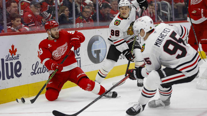 Jan 10, 2025; Detroit, Michigan, USA; Detroit Red Wings right wing Alex DeBrincat (93) passes the puck under pressure from Chicago Blackhawks right wing Ilya Mikheyev (95) and center Connor Bedard (98) at Little Caesars Arena. Mandatory Credit: Brian Bradshaw Sevald-Imagn Images