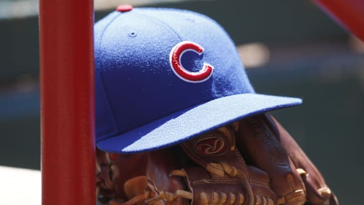 A Chicago Cubs hat and glove sits in the dugout during a game