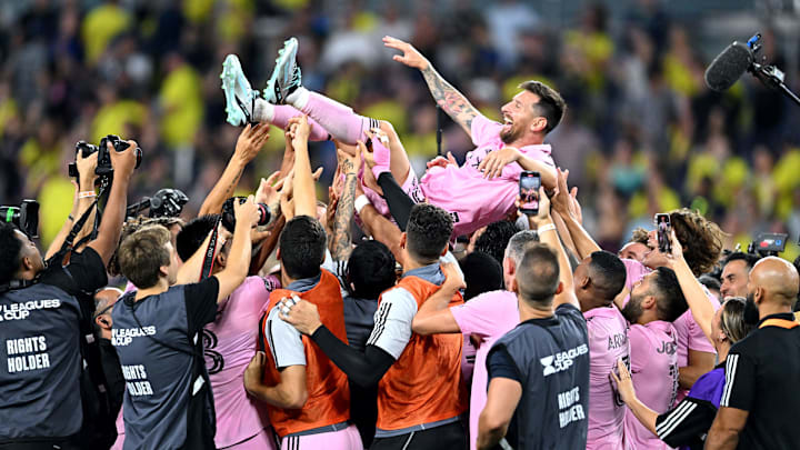 Inter Miami CF players toss a joyous Lionel Messi into the air while, in the background, yellow-clad Nashville SC fans head for the exits at Geodis Park after the Herons won a penalty-kick shootout to claim the 2023 Leagues Cup.