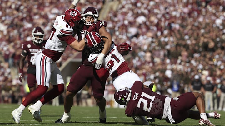 Nov 15, 2025; College Station, Texas, USA; Texas A&M Aggies defensive end T.J. Searcy (18) and linebacker Taurean York (21) attempt to tackle South Carolina Gamecocks running back Rahsul Faison (1) on a play during the second quarter at Kyle Field. Mandatory Credit: Troy Taormina-Imagn Images