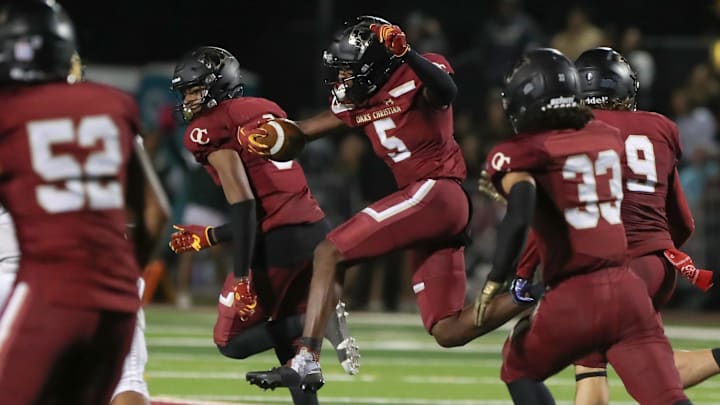 Oaks Christian's Davon Benjamin leaps through an opening after making an interception of a St. Bonaventure pass during the third quarter of the Marmonte League title game on Friday, Oct. 27, 2023, at Oak Christian's Thorson Stadium. Oaks Christian won 13-10.