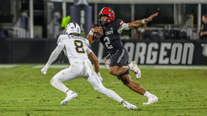 Aug 28, 2025; Orlando, Florida, USA; Jacksonville State Gamecocks quarterback Gavin Wimsatt (2) carries the ball as UCF Knights defensive back Demari Henderson (8) moves in during the second half at Acrisure Bounce House. Mandatory Credit: Mike Watters-Imagn Images