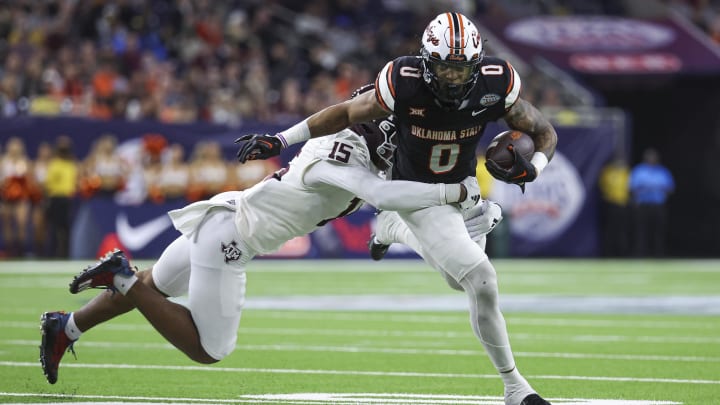 Dec 27, 2023; Houston, TX, USA; Oklahoma State Cowboys running back Ollie Gordon II (0) runs with the ball as Texas A&M Aggies defensive lineman Rylan Kennedy (15) attempts to make a tackle during the third quarter at NRG Stadium. Mandatory Credit: Troy Taormina-USA TODAY Sports
