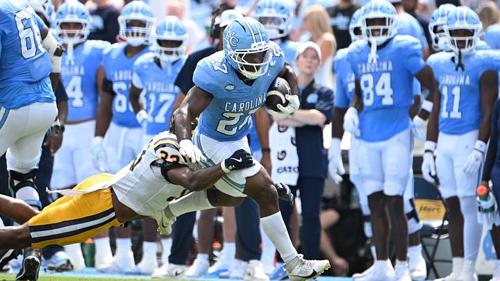 Sep 12, 2026; Chapel Hill, North Carolina, USA; North Carolina Tar Heels running back Jaylen McGill (27) with the ball as ETSU Buccaneers linebacker Dre Delinois (33) defends in the second quarter at Kenan Stadium. Mandatory Credit: Bob Donnan-Imagn Images Sep 12, 2026; Chapel Hill, North Carolina, USA; North Carolina Tar Heels running back Jaylen McGill (27) with the ball as ETSU Buccaneers linebacker Dre Delinois (33) defends in the second quarter at Kenan Stadium. Mandatory Credit: Bob Donnan-Imagn Images