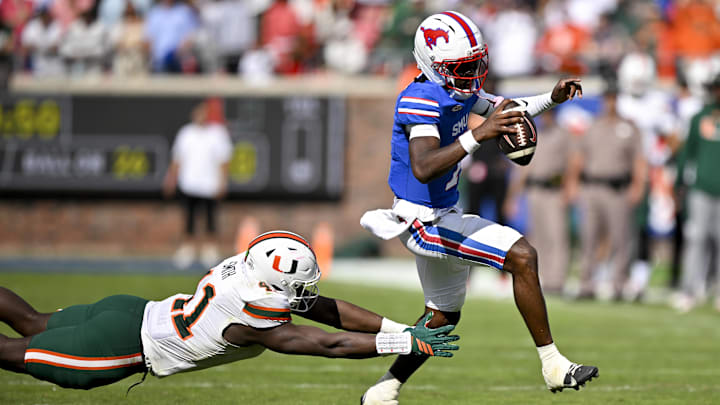 SMU Mustangs quarterback Kevin Jennings runs with the ball and eludes a Miami Hurricanes defensive lineman. Mandatory Credit: Jerome Miron-Imagn Images