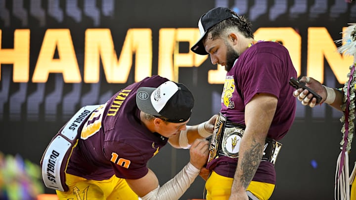 Dec 7, 2024; Arlington, TX, USA; Arizona State Sun Devils quarterback Sam Leavitt (10) signs the WWE Big 12 championship belt of running back Cam Skattebo (4) celebrates after the Sun Devils defeat the Iowa State Cyclones and win the 2024 Big 12 Championship at AT&T Stadium. Mandatory Credit: Jerome Miron-Imagn Images