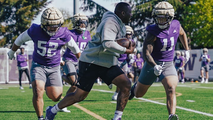 Voi Tunuufi (52) and Alphonzo Tuputala (11) chase after a ball-carrying coach in spring ball. 