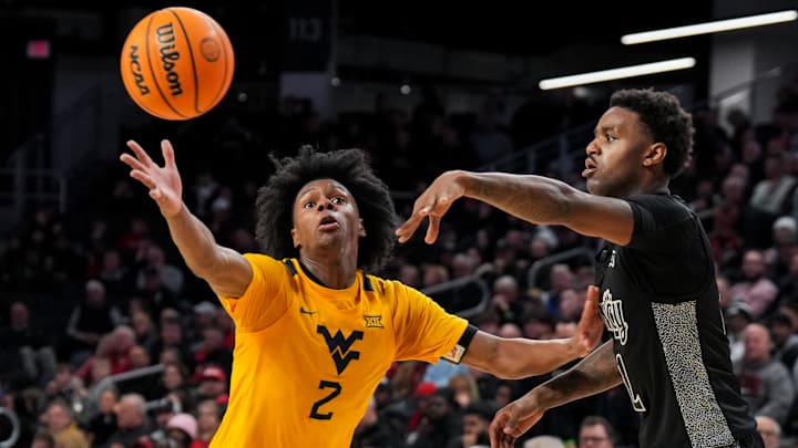 Feb 5, 2026; Cincinnati, Ohio, USA;  Cincinnati Bearcats guard Jizzle James (2) passes the ball against West Virginia Mountaineers guard Amir Jenkins (2) in the second half at Fifth Third Arena. Mandatory Credit: Aaron Doster-Imagn Images