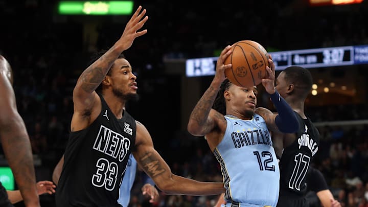 Dec 13, 2024; Memphis, Tennessee, USA; Memphis Grizzlies guard Ja Morant (12) drives to the basket as Brooklyn Nets center Nic Claxton (33) and Brooklyn Nets guard Dennis Schroder (17) defends during the fourth quarter at FedExForum. Mandatory Credit: Petre Thomas-Imagn Images