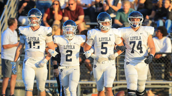 Loyola football players lock arms as they approach midfield for the coin toss before taking on Cathedral.