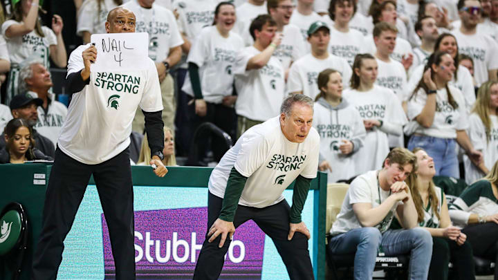 Michigan State coach Tom Izzo watches a play as assistant coach Mark Montgomery holds up a sign