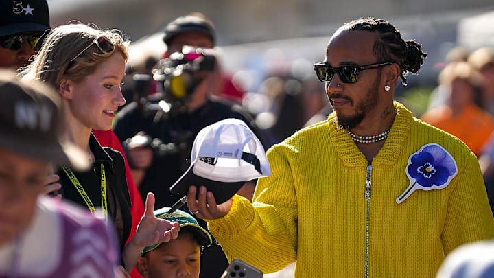 Oct 20, 2024; Austin, Texas, USA; Mercedes-AMG Petronas driver Lewis Hamilton returns a signed hat to F1 fan Lyla Windsor in the paddock at the Formula 1 Pirelli United States Grand Prix at Circuit of the Americas. Mandatory Credit: Aaron E. Martinez-Imagn Images