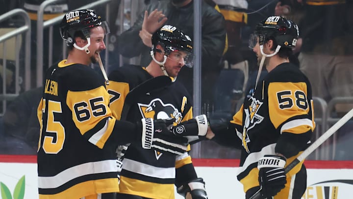 Mar 30, 2025; Pittsburgh, Pennsylvania, USA;  Pittsburgh Penguins defenseman Erik Karlsson (65) and center Sidney Crosby (middle) and defenseman Kris Letang (58) celebrate after defeating the Ottawa Senators in overtime at PPG Paints Arena. Mandatory Credit: Charles LeClaire-Imagn Images