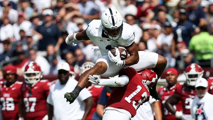 Penn State Nittany Lions running back James Peoples (1) hurdles Temple Owls cornerback Denzel Chavis (13). 