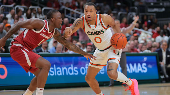 Dec 3, 2024; Coral Gables, Florida, USA; Miami Hurricanes guard Matthew Cleveland (0) drives to the basket past Arkansas Razorbacks guard Johnell Davis (1) during the second half at Watsco Center. Mandatory Credit: Sam Navarro-Imagn Images