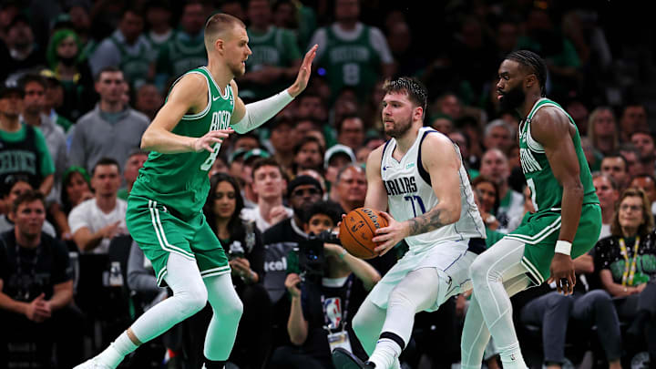 Jun 17, 2024; Boston, Massachusetts, USA; Dallas Mavericks guard Luka Doncic (77) handles the ball against Boston Celtics guard Jaylen Brown (7) and center Kristaps Porzingis (8) in game five of the 2024 NBA Finals at TD Garden. Mandatory Credit: Peter Casey-Imagn Images