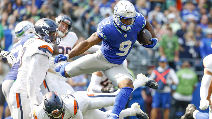 Sep 8, 2024; Seattle, Washington, USA; Seattle Seahawks running back Kenneth Walker III (9) jumps over a tackle attempt by Denver Broncos cornerback JaQuan McMillian (29) during the second quarter at Lumen Field. Mandatory Credit: Joe Nicholson-Imagn Images