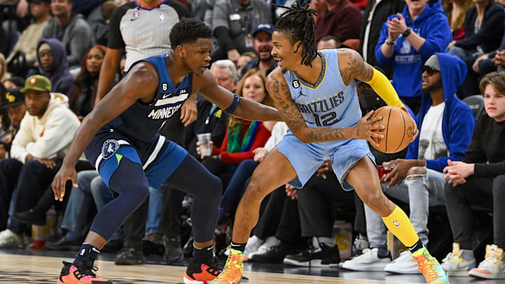   Memphis Grizzlies guard Ja Morant (12) protects the ball as Minnesota Timberwolves forward Anthony Edwards (1) defends during the second quarter at Target Center. Mandatory Credit: Nick Wosika-Imagn Images